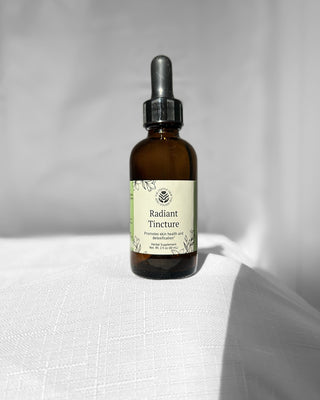radiant herbal tincture by the fertile glow in a 2 ounce dropper bottle on a white background. label says radiant herbal supplement supports skin health and detoxification. tan and green label with black flowers.