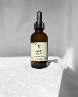 digestive bitters herbal blend by the fertile glow in a 2 ounce amber dropper bottle with a white background. label says digestive bitters herbal supplement supports healthy digestion and gut health. Tan and green label with black flowers.