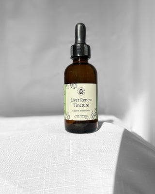 liver renew herbal tincture by the fertile glow in a 2 ounce dropper bottle on a white background. Label says liver renew herbal supplement supports detoxification. Tan and green label with black flowers.